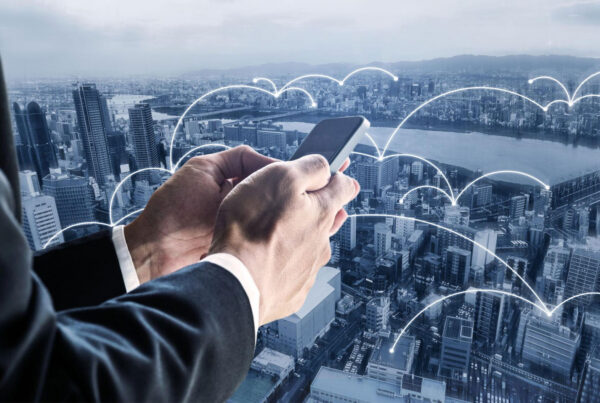 Businessperson holding a smartphone over a city skyline with glowing network connections.